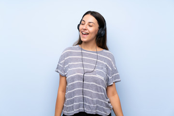 Fototapeta premium Young brunette woman over isolated blue background listening to music with headphones