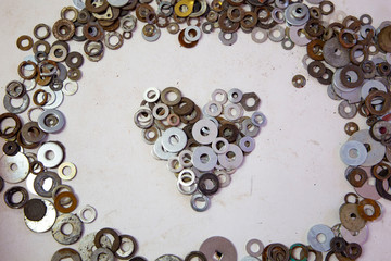 Vintage and rusty metal rings and washers in shape of heart on the workshop desk. Concept of male craft, professional fix and repair