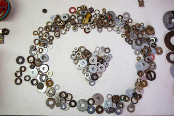 Vintage and rusty metal rings and washers in shape of heart on the workshop desk. Concept of male craft, professional fix and repair