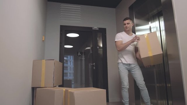 Young guy takes boxes with things that his girlfriend from elevator gives him