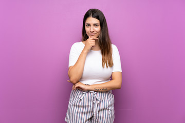 Young woman over isolated purple background thinking