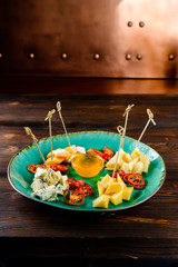 Wine appetizer set. parmesan cheese, dried tomatoes on round ceramic plate over wood backdrop