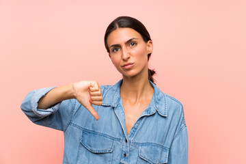 Young woman over isolated pink background showing thumb down sign
