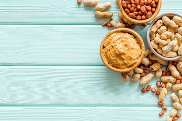 nuts in bowl for peanut butter for cooking breakfast at home on mint green wooden background top...