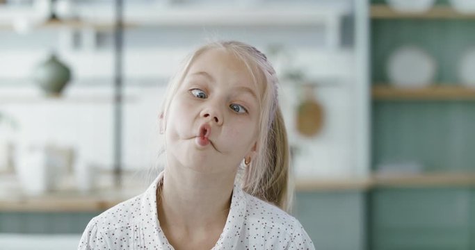 FIXED Portrait of little cute Caucasian girl doing silly funny face, looking into camera. 60 FPS Slow Motion, 4K RAW graded footage