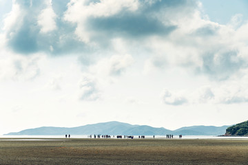 Obraz premium Landscape of low tide with green mountain, cloud sky with people in background at Toong Pronge Bay in Chon Buri, Sattahip District, Thailand.