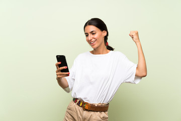 Young woman over isolated green background using mobile phone