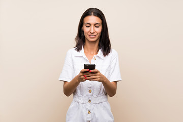 Young woman over isolated background sending a message with the mobile