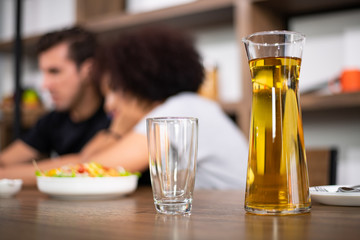 Young couple is feeding each other and smiling while cooking salad and hamburger in kitchen