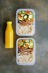 Balanced nutritious lunch in plastic container. Turkey breast with brown rice and vegetables. Fresh orange juice in a bottle