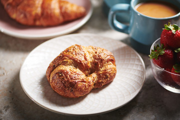 Croissant on White Plate with Assorted Breakfast Pastries and Coffee