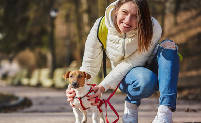 Happy young woman walking with jack russell dog in the park.
