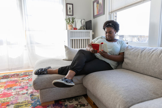 Young woman on couch reading a book