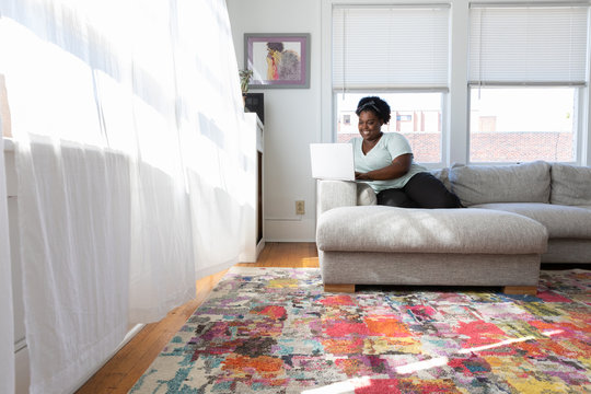 Woman working on her laptop sitting on couch