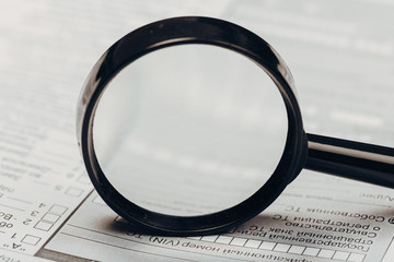Fototapeta premium Small magnifying glass on paper with text. search, analysis