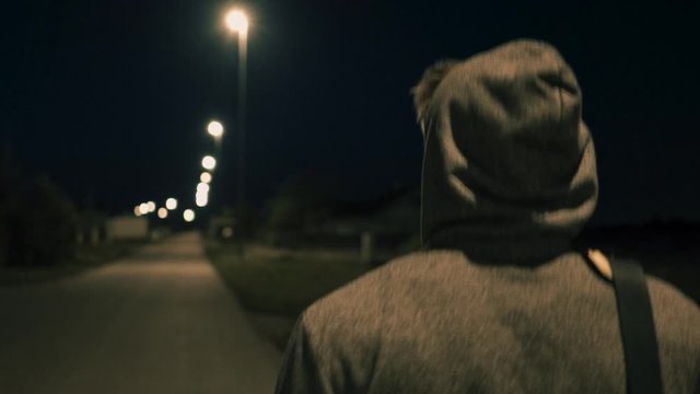 Follow back of a Man walking in the street with a sporty shoulder bag. A strange guy in a hoodie with a ruffle gym bag, no face.