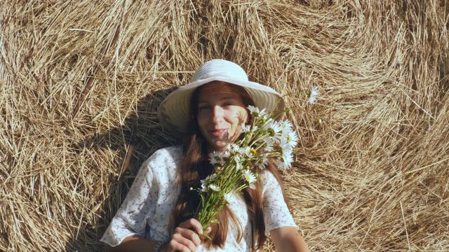 Cheerful woman with flowers against haystack