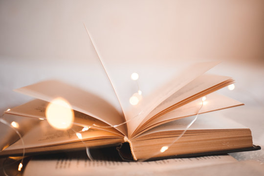 Open book with magic Christmas lights closeup. Selective focus. Good morning. Night time.