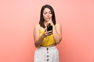 Young Mexican woman over isolated wall thinking and sending a message