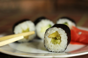 Japanese roll with cucumber on plate and wooden sticks