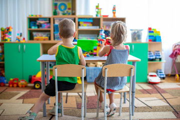 Children play in the designer at the table. Two child girl and boy  play together with colored plastic blocks in the gaming center, school.