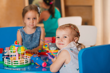 Little cute girls play in the room. Development and social learning