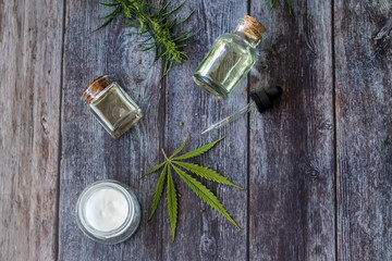 Cannabis hemp creams with marijuana leaf on wooden background - topical cannabis oil concept