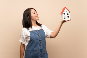 Fototapeta na wymiar Young Mexican woman over isolated background holding a little house