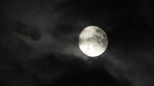 Moon With Clouds In The Night Sky. Concept of a spooky theme and mystery. Mysterious night sky with moon and dramatic clouds passing. Dark night with moon.