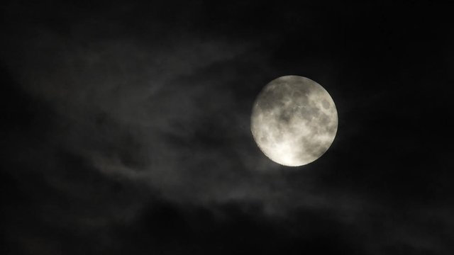 Moon With Clouds In The Night Sky. Concept of a spooky theme and mystery. Mysterious night sky with moon and dramatic clouds passing. Dark night with moon.