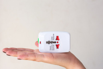 Close up of woman hand holding universal electric socket plug adapters, isolated on white...