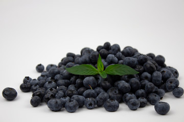 Blueberries on a white background. A bunch of ripe blueberries with green leaves with copy space for text. Blueberries on a white background. Copyspace