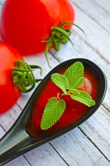 Tomato paste with ripe tomatoes on a wooden table.
