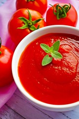 Tomato paste with ripe tomatoes on a wooden table.