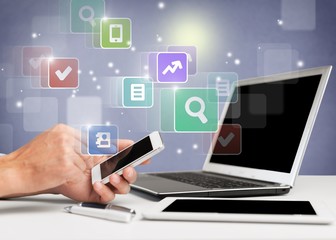 Male hands with phone on laptop  on office table