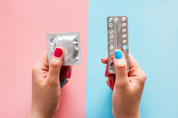 woman holding contraceptives - condom and birth control pills