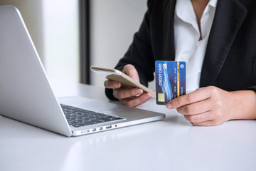 Young woman consumer holding smartphone, credit card and typing on laptop for online shopping and payment make a purchase on the Internet, Online payment, networking and buy product technology