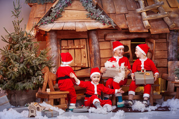A group of four children in a Christmas hat and costumes with gifts near a fabulous house