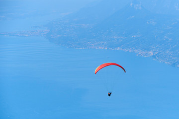 Paraglider flying over the Garda Lake (Lago di Garda or Lago Benaco). Paragliding on Monte Baldo. Panorama of the gorgeous Garda lake surrounded by mountains, Malcesine, Italy