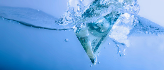 Money concept. US Dollar sinking in water as symbol of global financiall crisis and economic downturn