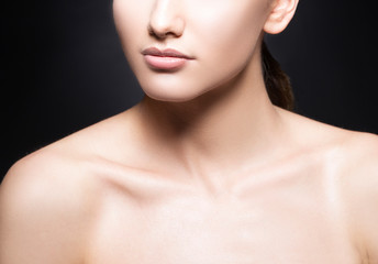 Lips, part of beauty face, shoulders of beautiful young model woman, perfect skin, natural nude makeup. Black background