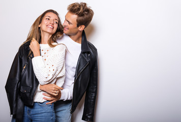 Young beautiful couple in black leather jackets pose in studio.