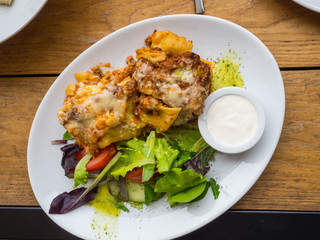Tasty serving of traditional Italian lasagne with spicy tomato based ground beef and melted mozzarella cheese between layers of noodles, with cream and green leafs