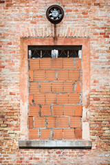 Front view of brick building, walled window and fan