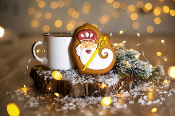 Holiday traditional food bakery. Gingerbread old kindly wizard in cozy decoration with garland lights and cup of hot coffee