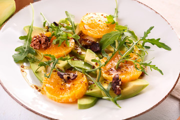 Fototapeta na wymiar fresh avocado and orange salad on a beige plate