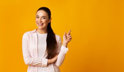 Positive Girl Pointing Finger At Free Space On Yellow Background