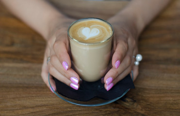 A glass of cappuccino in female hands
