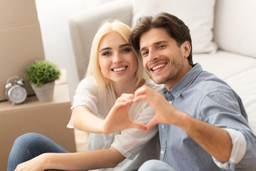 Couple Making Heart Shape With Their Hands In New Home
