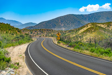 Curved mountain road with 30 MPH caution road sign